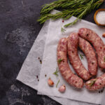 Raw,Sausages,And,Ingredients,For,Cooking,On,A,Black,Stone