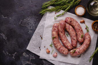 Raw,Sausages,And,Ingredients,For,Cooking,On,A,Black,Stone