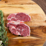 Raw,Lamb,Chump,Slices,On,Chopping,Board,With,Herbs