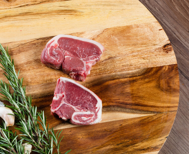 Raw,Lamb,Loin,Slices,On,Chopping,Board,With,Herbs